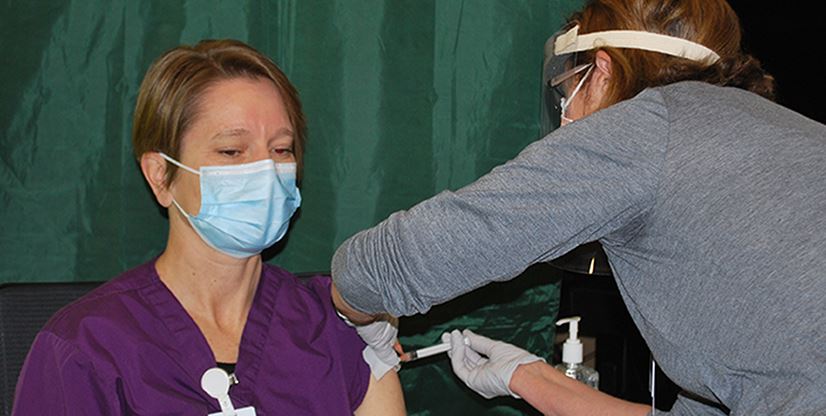 doctor administering vaccine to a female patient
