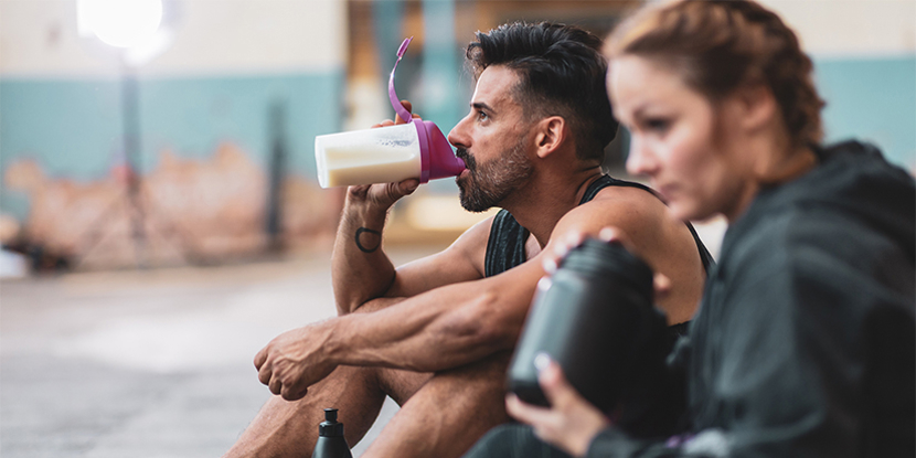 man and woman at gym drinking shakes