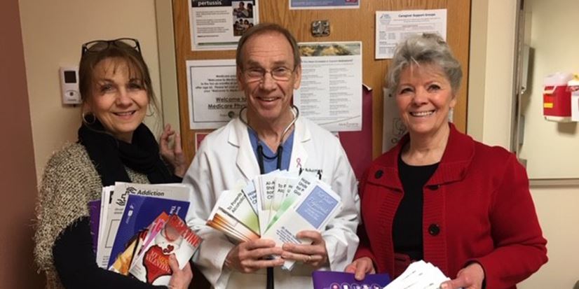 2 women and a male doctor holding pamphlets