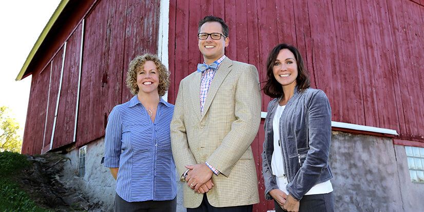 three people standing outside a red building