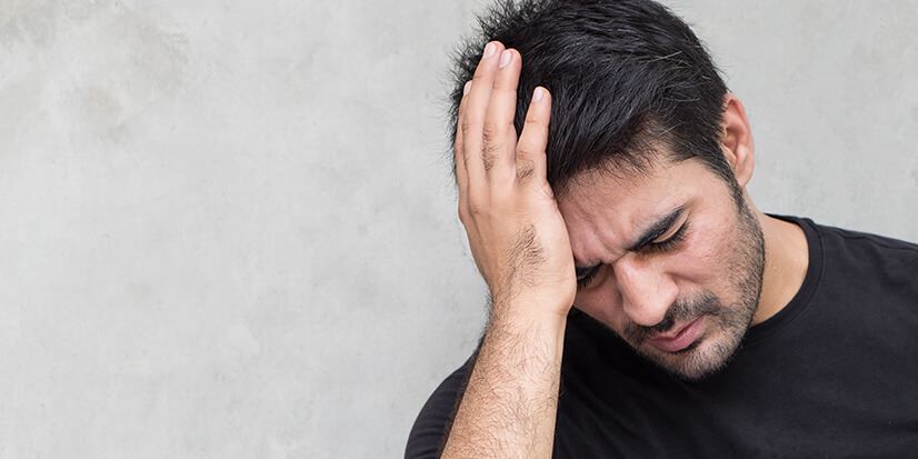 man in anguish holding his head