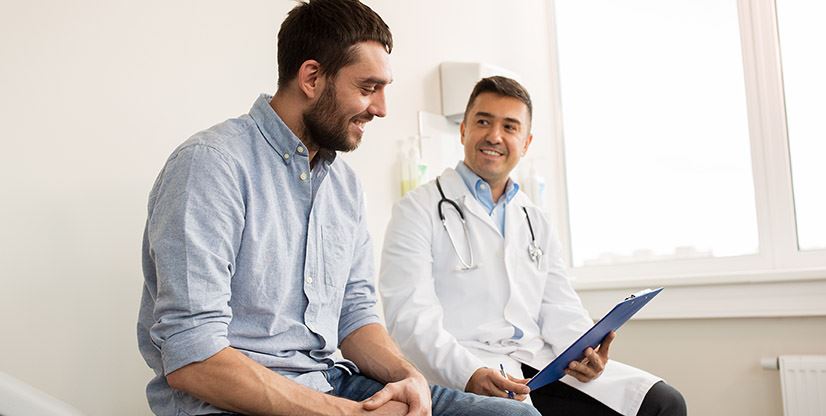 man talking to a doctor and looking at the clipboard