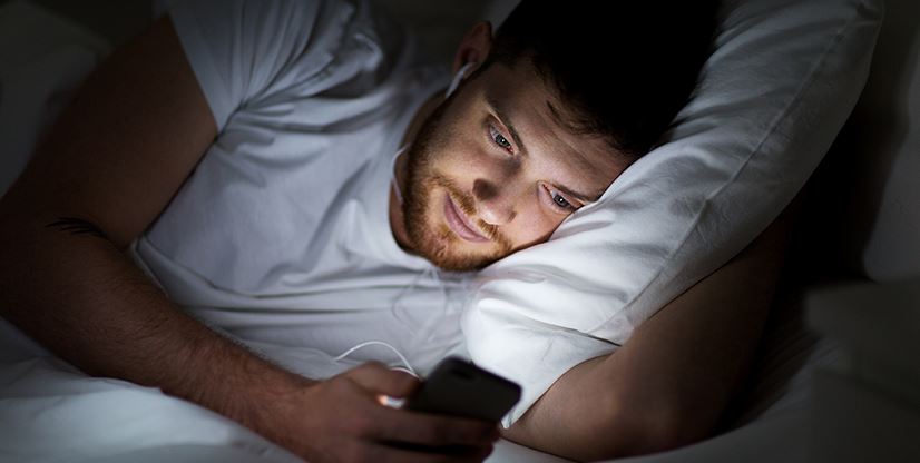 man in bed on his cell phone