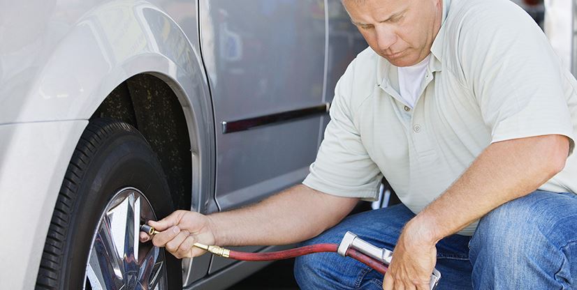 man checking tire pressure on a car