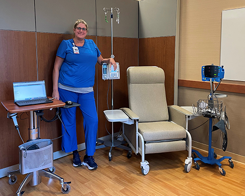 woman stands by infusion chair in clinic