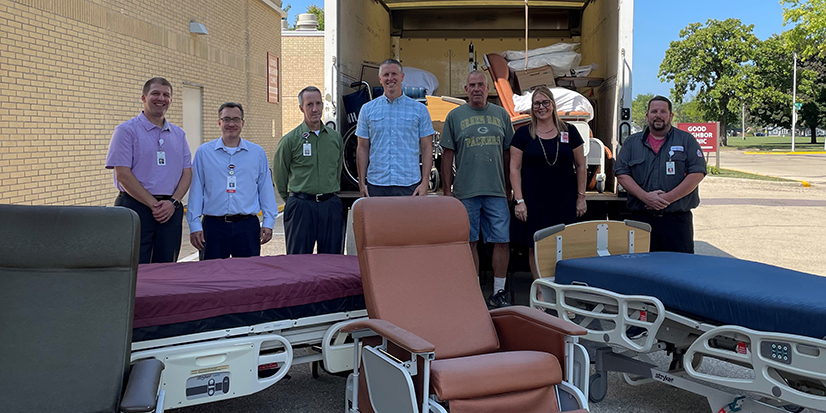 group stands by open moving track and hospital beds outside