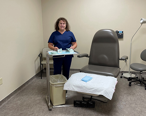 provider stands next to clinic exam room chair